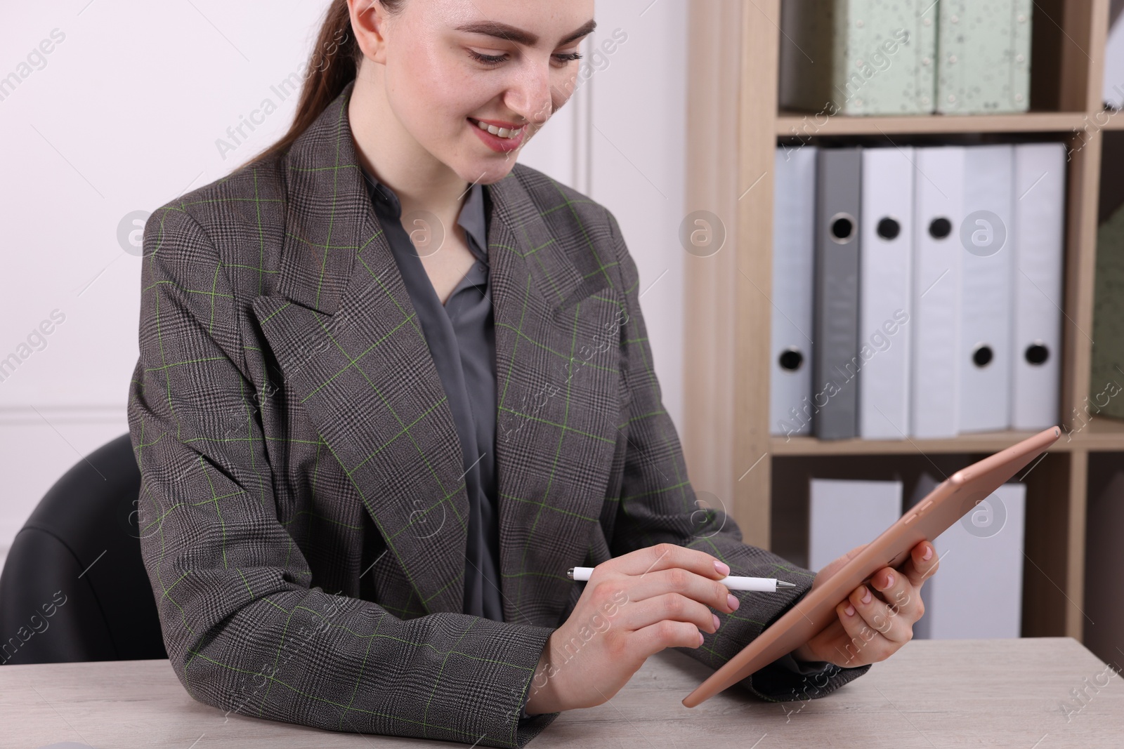 Photo of Electronic signature. Woman using stylus and tablet at wooden table indoors, closeup