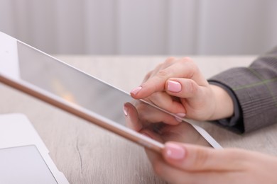 Photo of Electronic signature. Woman using tablet at wooden table, closeup