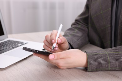 Photo of Electronic signature. Woman using stylus and smartphone at wooden table indoors, closeup