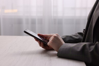 Photo of Electronic signature. Woman using smartphone at wooden table indoors, closeup