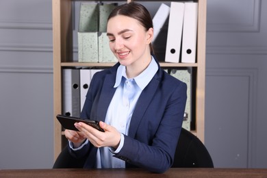 Photo of Electronic signature. Woman using smartphone in office