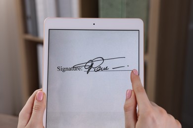 Photo of Electronic signature. Woman using tablet indoors, closeup