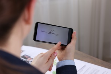 Photo of Electronic signature. Woman using smartphone indoors, closeup