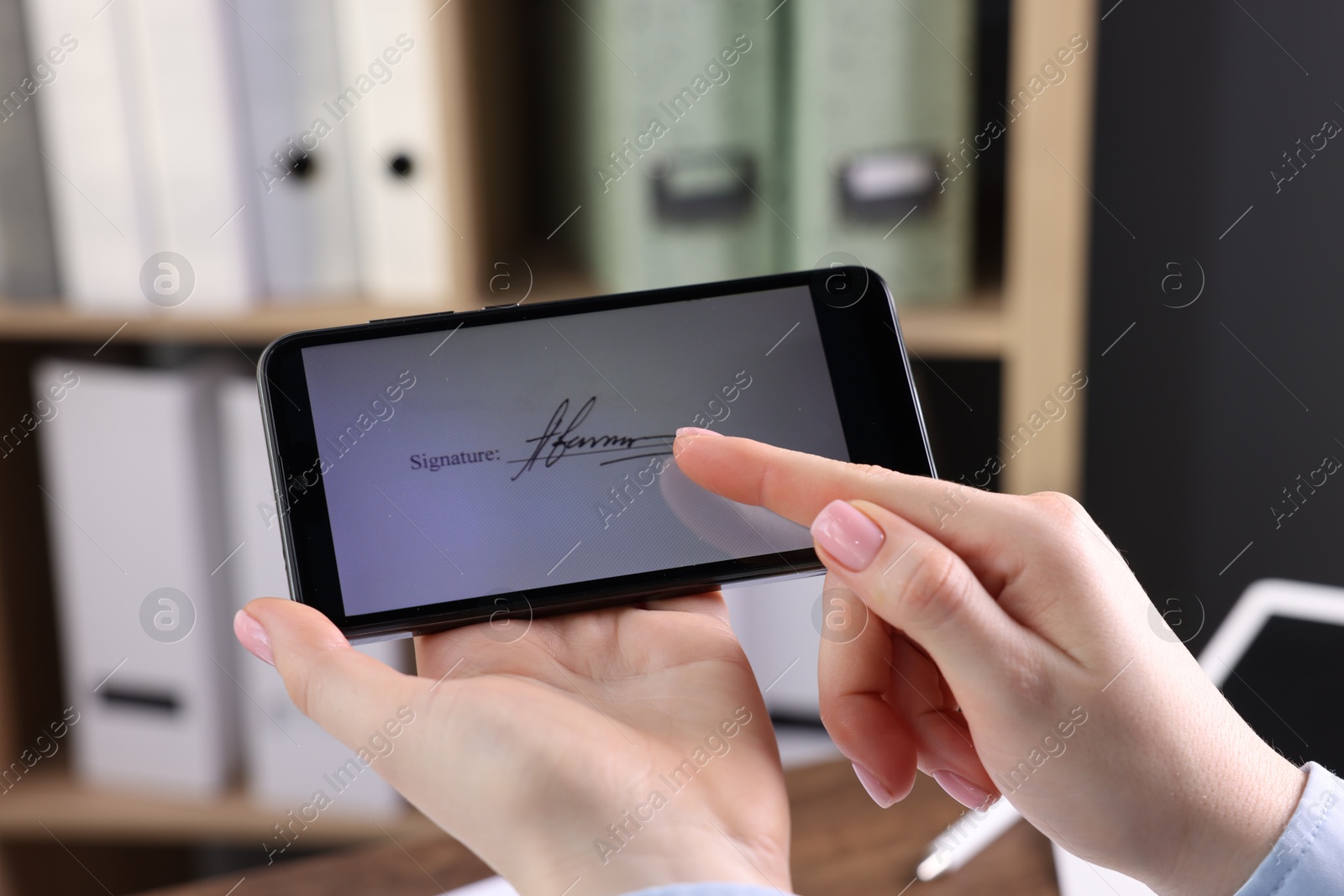 Photo of Electronic signature. Woman using smartphone indoors, closeup