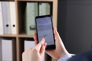 Photo of Electronic signature. Woman using smartphone indoors, closeup