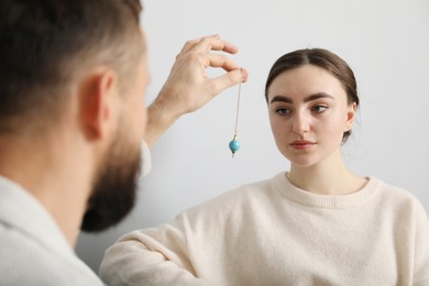 Photo of Psychologist using pendulum while working with patient during hypnosis session indoors