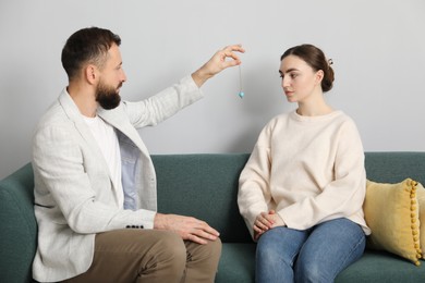 Photo of Psychologist using pendulum while working with patient during hypnosis session indoors