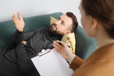 Photo of Psychologist working with patient during hypnosis session indoors