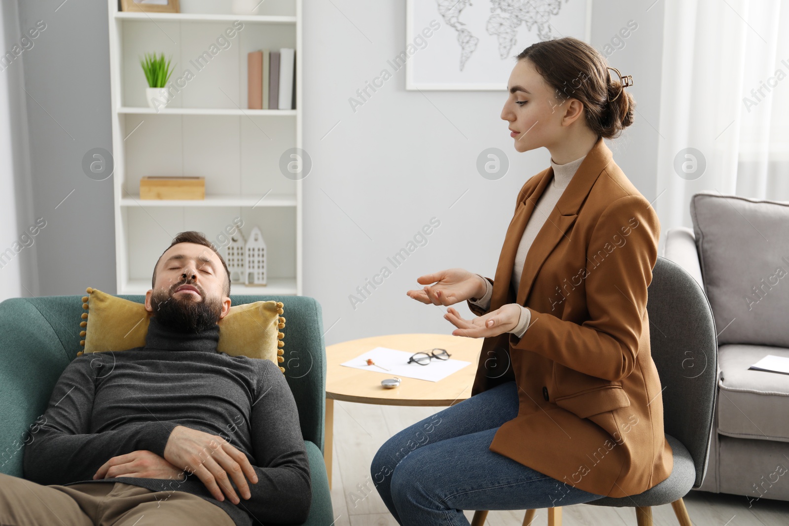 Photo of Psychologist working with patient during hypnosis session indoors