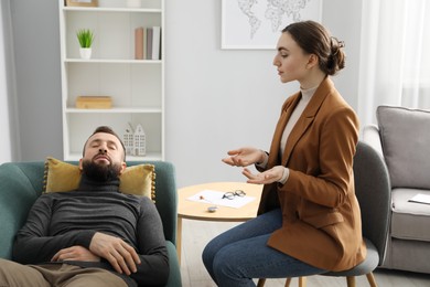 Photo of Psychologist working with patient during hypnosis session indoors