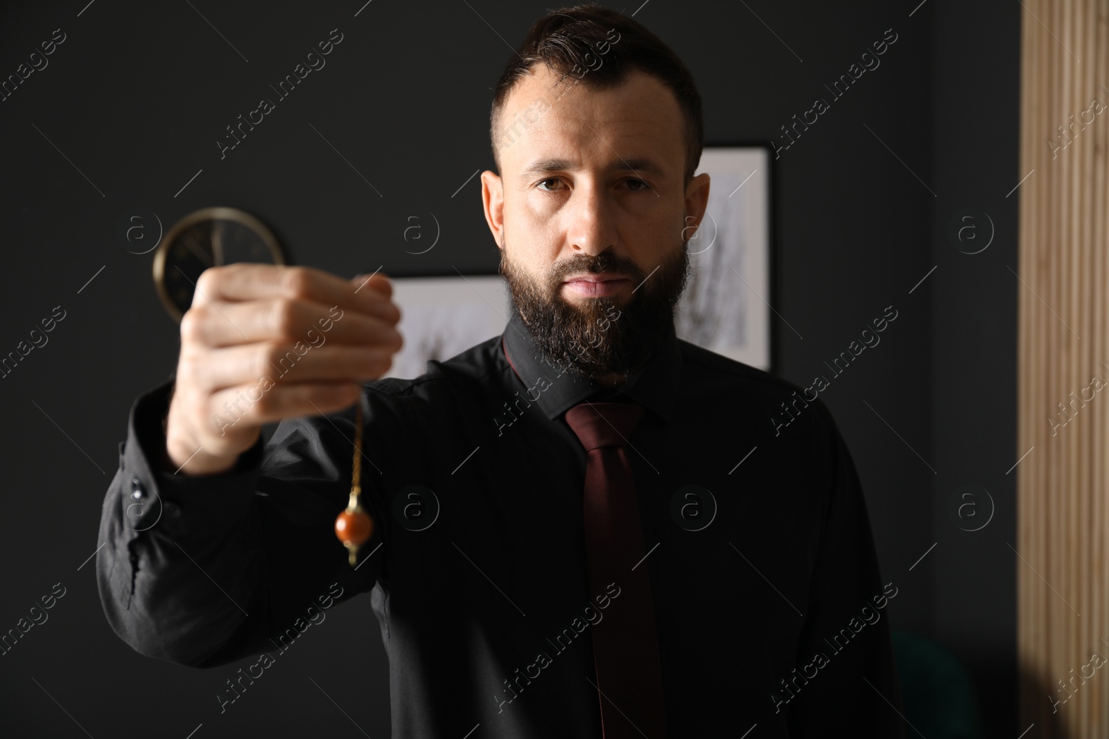 Photo of Hypnosis session. Man with pendulum in office