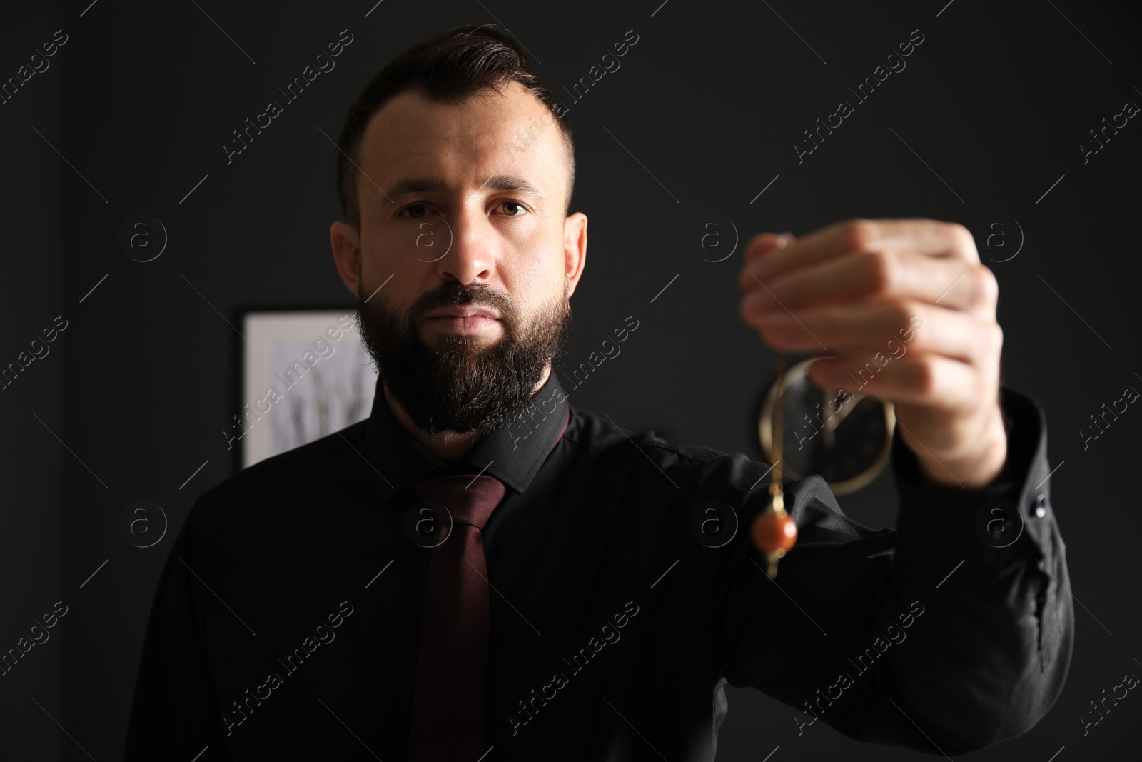 Photo of Hypnosis session. Man with pendulum in office