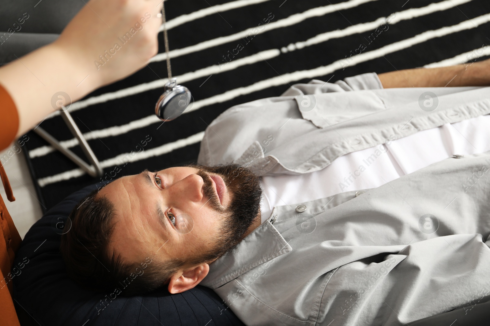 Photo of Psychologist using vintage pocket watch while working with patient during hypnosis session indoors, closeup