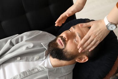 Photo of Psychologist working with patient during hypnosis session indoors, closeup