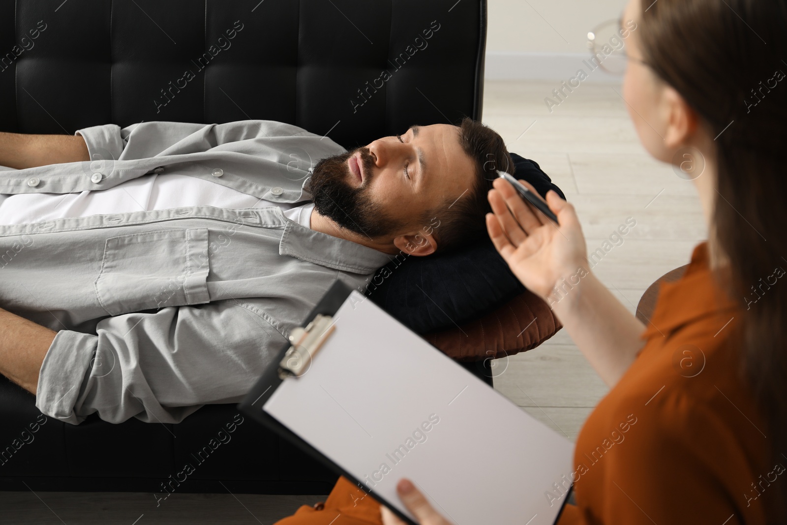 Photo of Psychologist working with patient during hypnosis session indoors