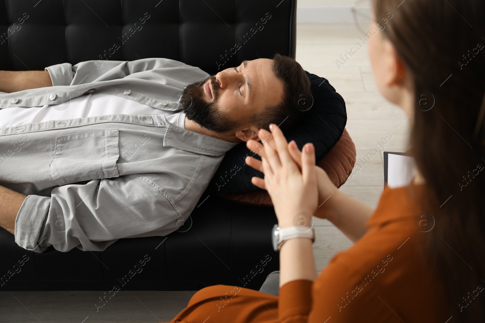 Photo of Psychologist working with patient during hypnosis session indoors, closeup