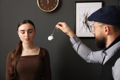 Photo of Psychologist using vintage pocket watch while working with patient during hypnosis session indoors