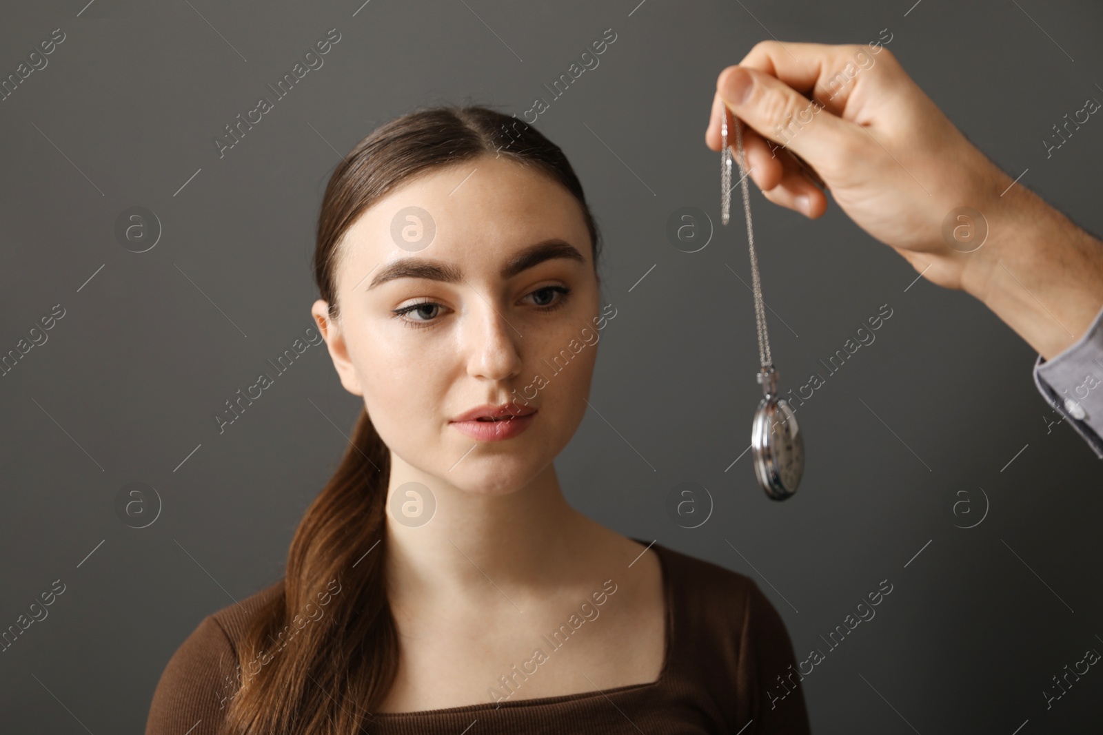 Photo of Psychologist using vintage pocket watch while working with patient during hypnosis session indoors, closeup