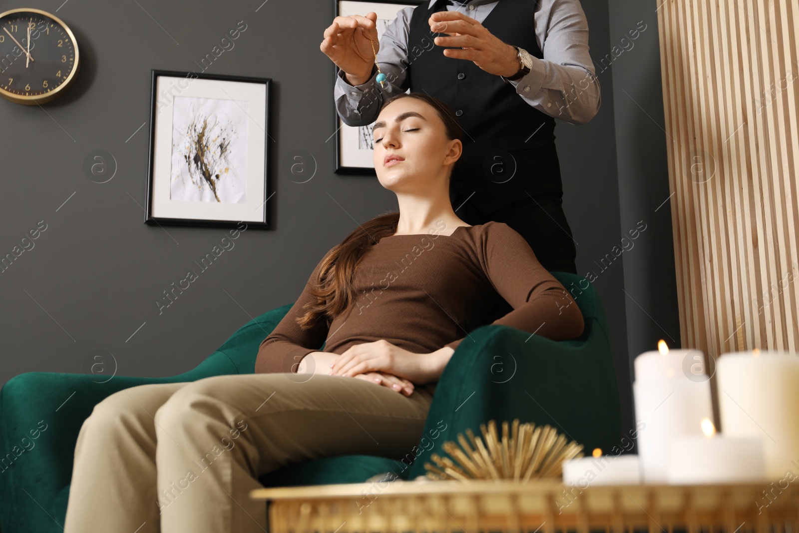 Photo of Psychologist using pendulum while working with patient during hypnosis session indoors, closeup