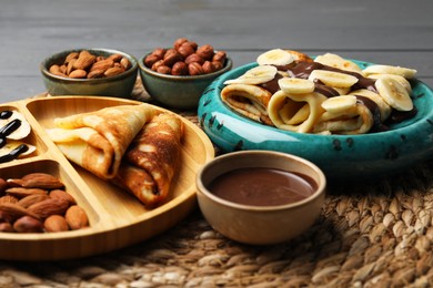 Delicious crepes served with chocolate paste and nuts on table, closeup