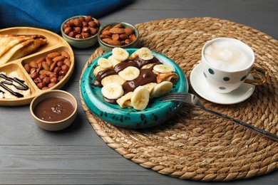 Delicious crepes served with chocolate paste, nuts and coffee on grey wooden table