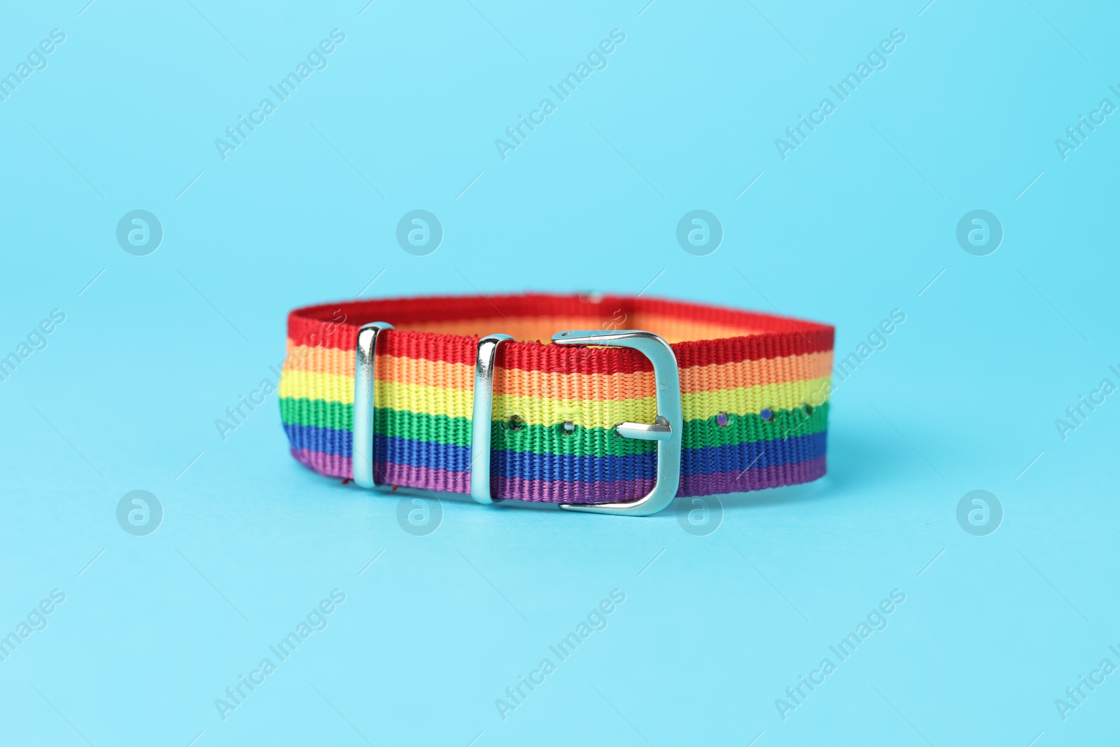 Photo of One wristband in LGBT colors on light blue background, closeup