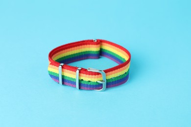 Photo of One wristband in LGBT colors on light blue background, closeup