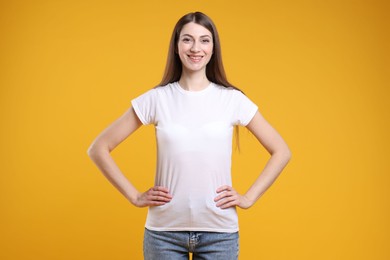 Photo of Woman wearing blank white t-shirt on orange background. Mockup for design