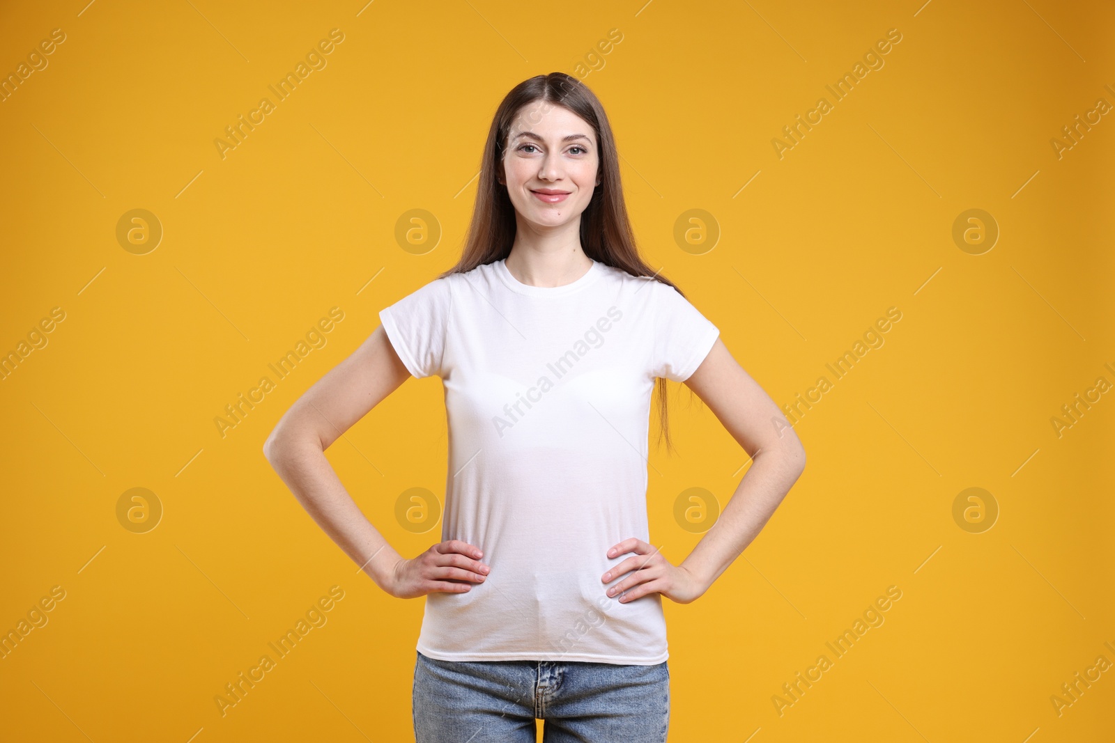 Photo of Woman wearing blank white t-shirt on orange background. Mockup for design