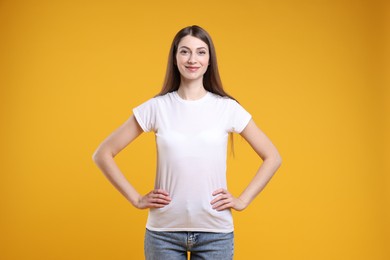 Photo of Woman wearing blank white t-shirt on orange background. Mockup for design