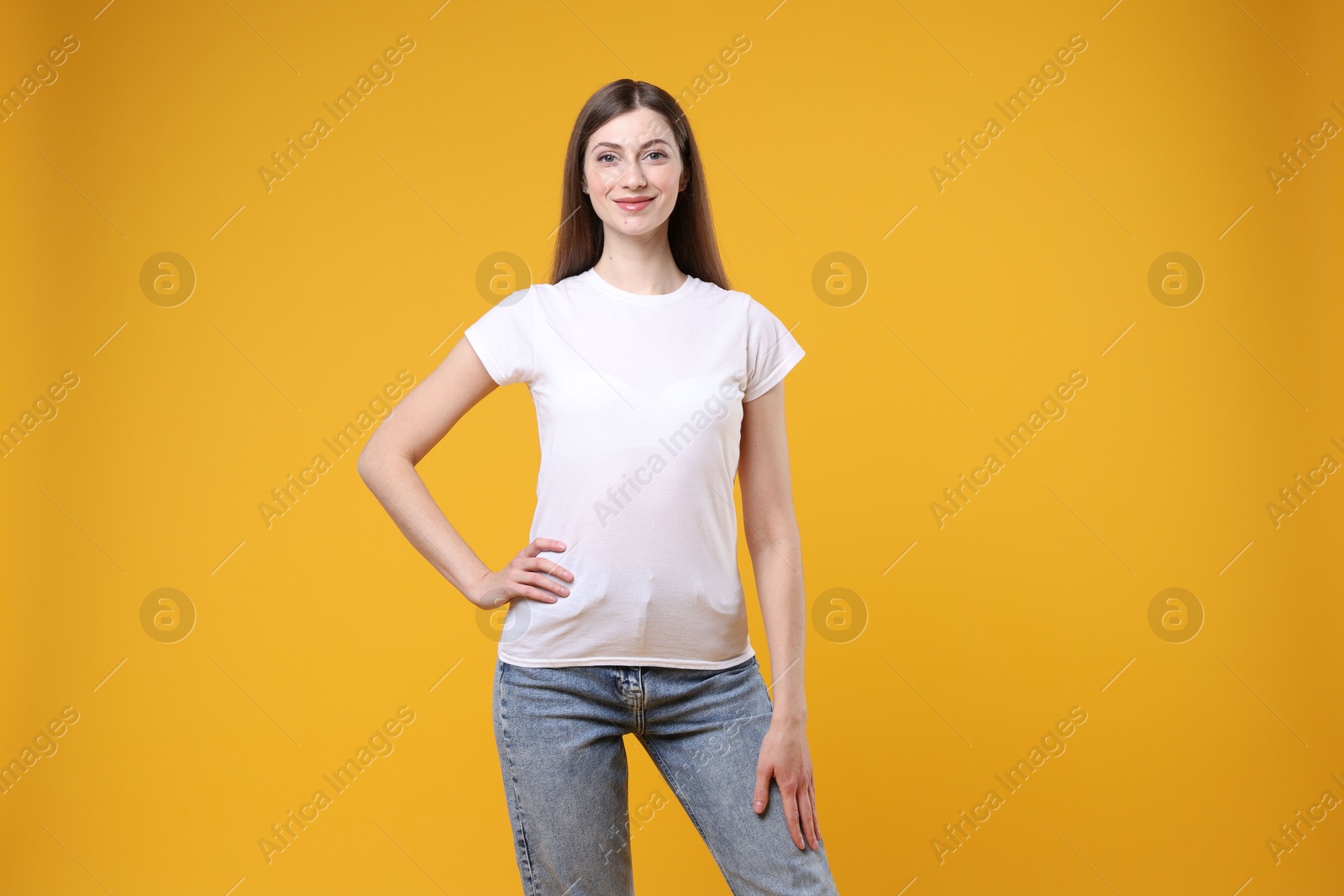 Photo of Woman wearing blank white t-shirt on orange background. Mockup for design