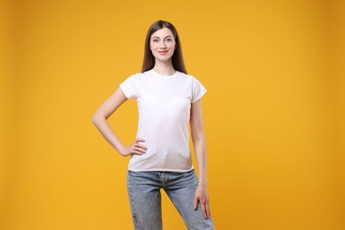 Photo of Woman wearing blank white t-shirt on orange background. Mockup for design