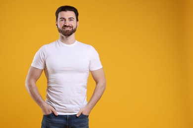 Photo of Man wearing blank white t-shirt on orange background. Mockup for design