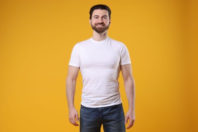 Photo of Man wearing blank white t-shirt on orange background. Mockup for design