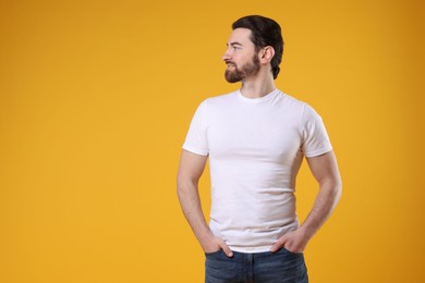 Photo of Man wearing blank white t-shirt on orange background. Mockup for design