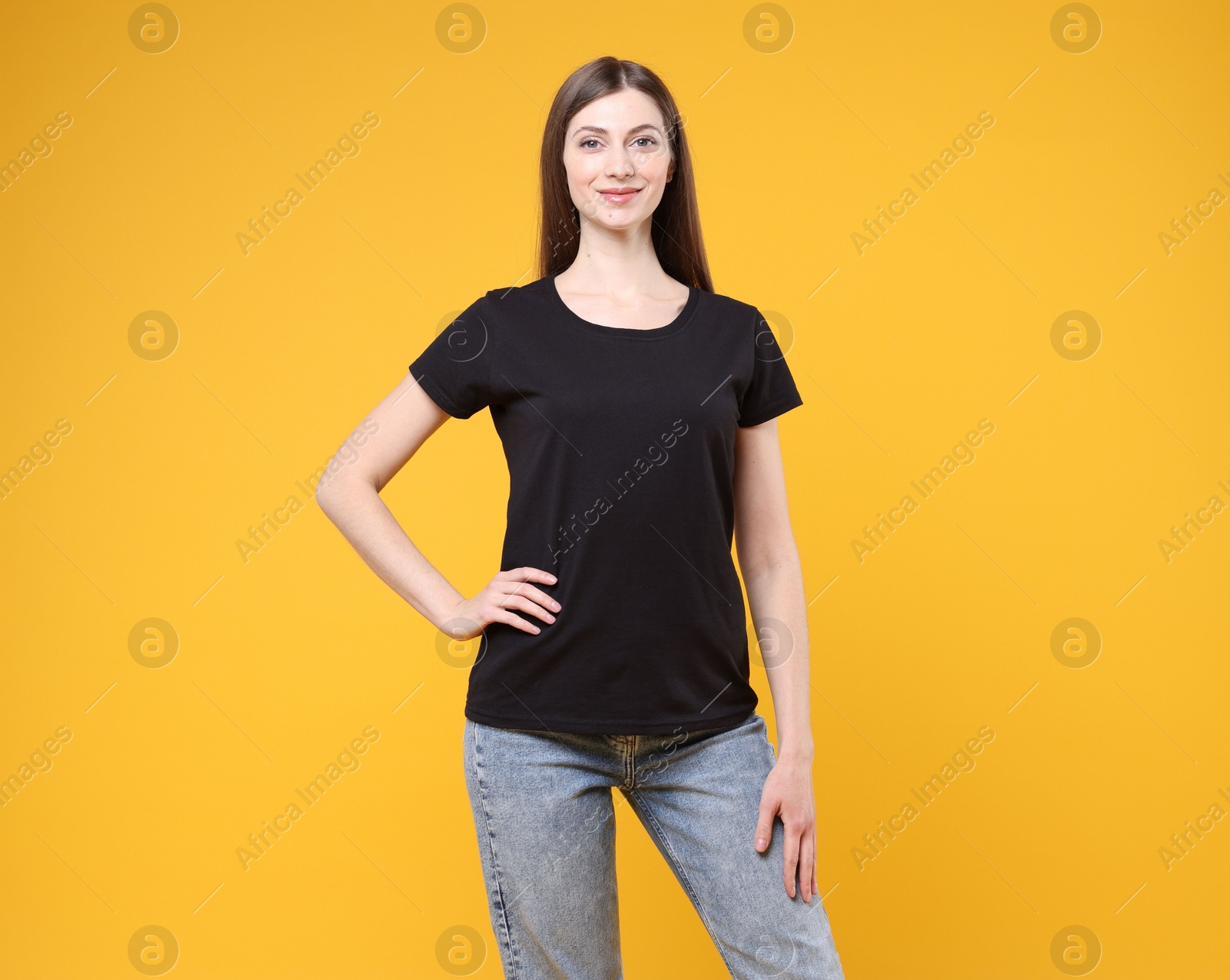 Photo of Woman wearing blank black t-shirt on orange background. Mockup for design