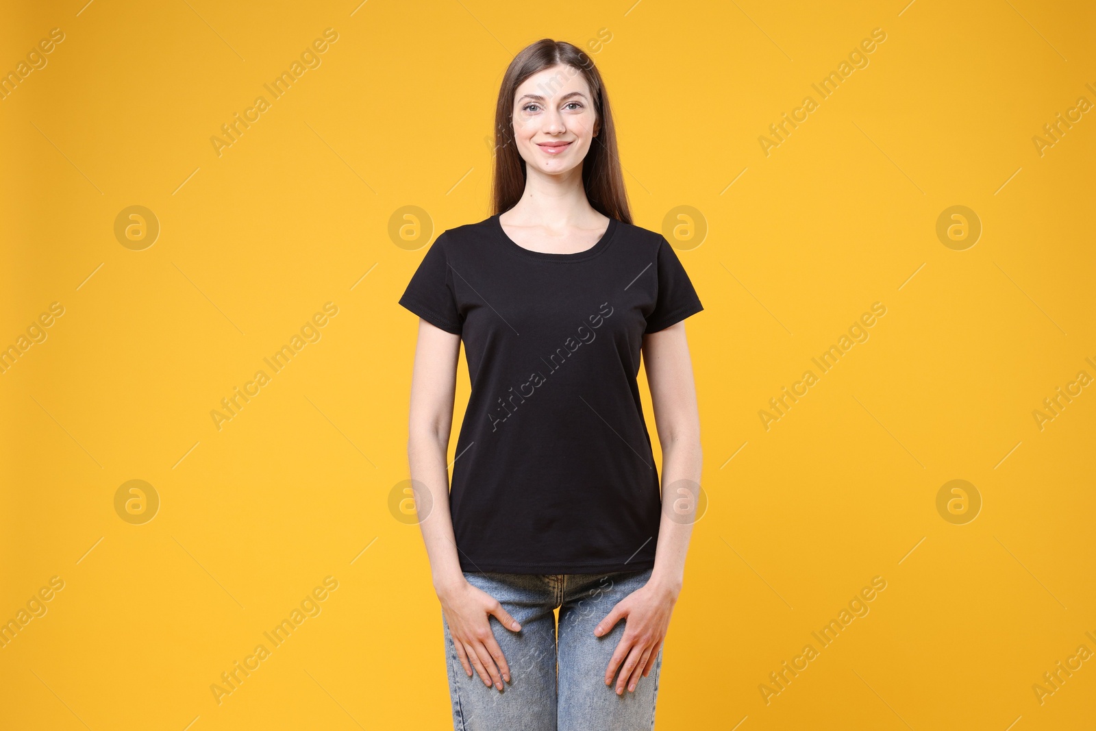 Photo of Woman wearing blank black t-shirt on orange background. Mockup for design