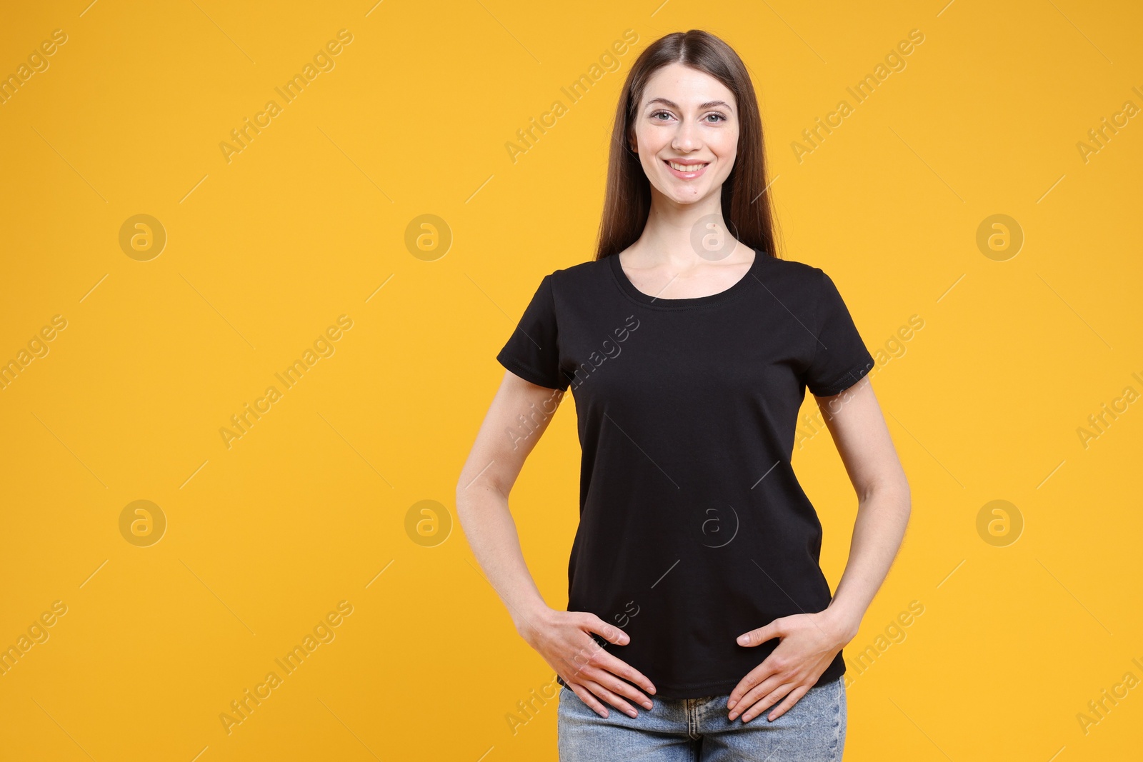 Photo of Woman wearing blank black t-shirt on orange background. Mockup for design