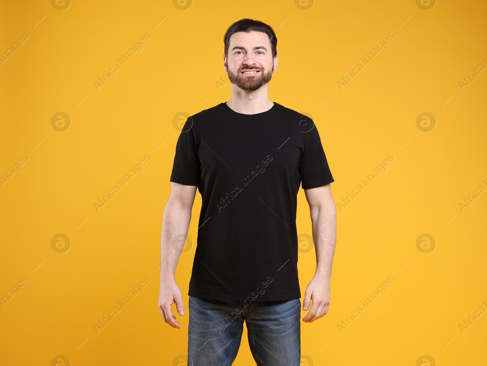 Photo of Man wearing blank black t-shirt on orange background. Mockup for design