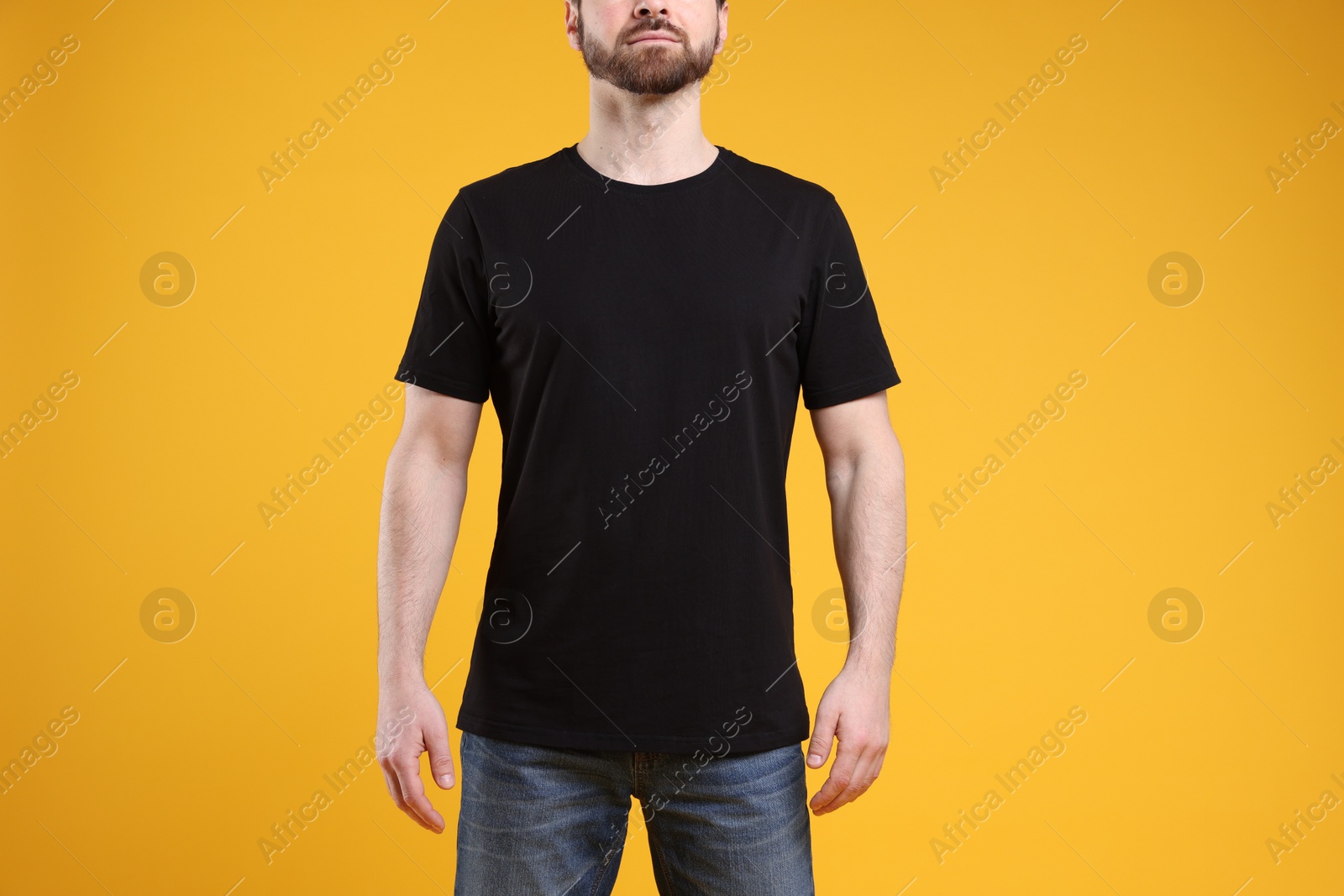 Photo of Man wearing blank black t-shirt on orange background, closeup. Mockup for design