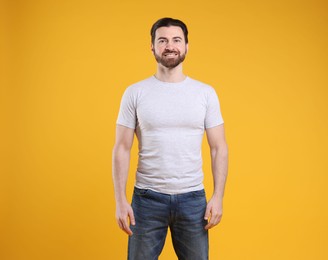 Photo of Man wearing blank white t-shirt on orange background. Mockup for design