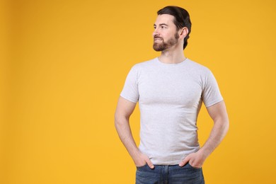 Photo of Man wearing blank white t-shirt on orange background. Mockup for design