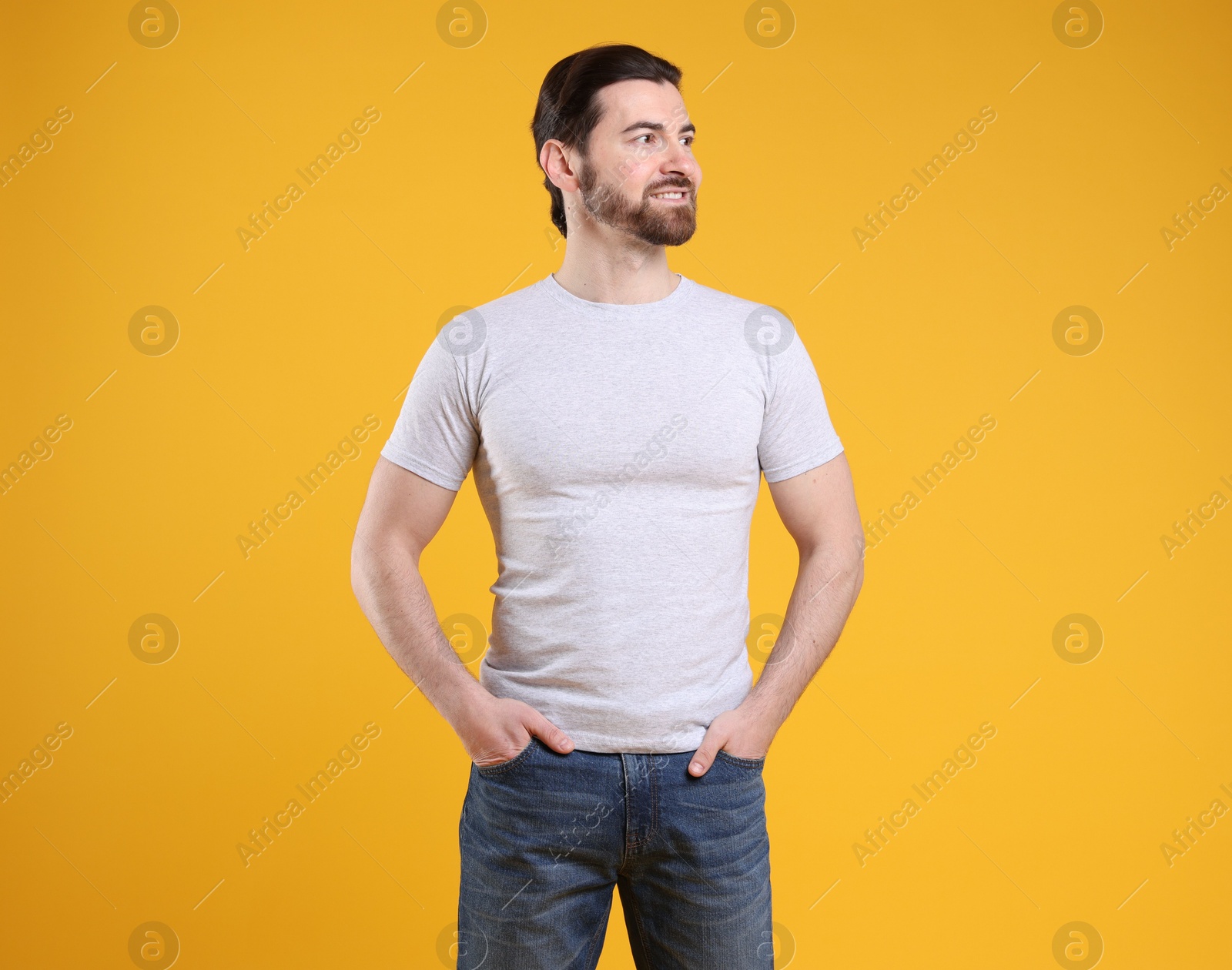 Photo of Man wearing blank white t-shirt on orange background. Mockup for design