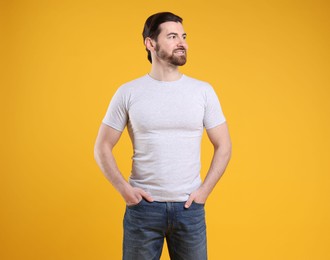 Photo of Man wearing blank white t-shirt on orange background. Mockup for design