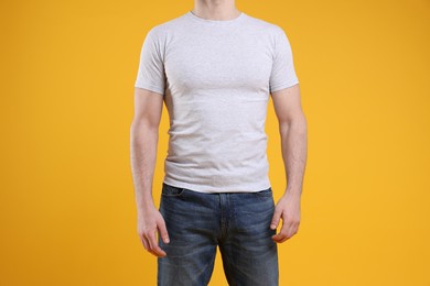 Photo of Man wearing blank white t-shirt on orange background, closeup. Mockup for design