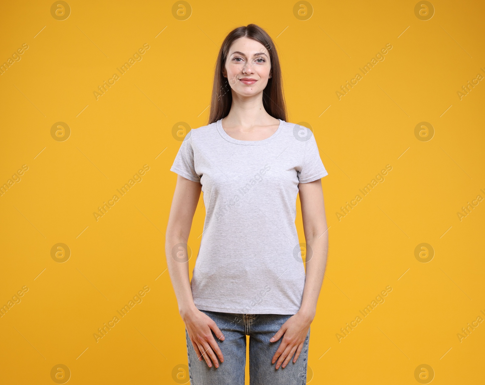 Photo of Woman wearing blank white t-shirt on orange background. Mockup for design