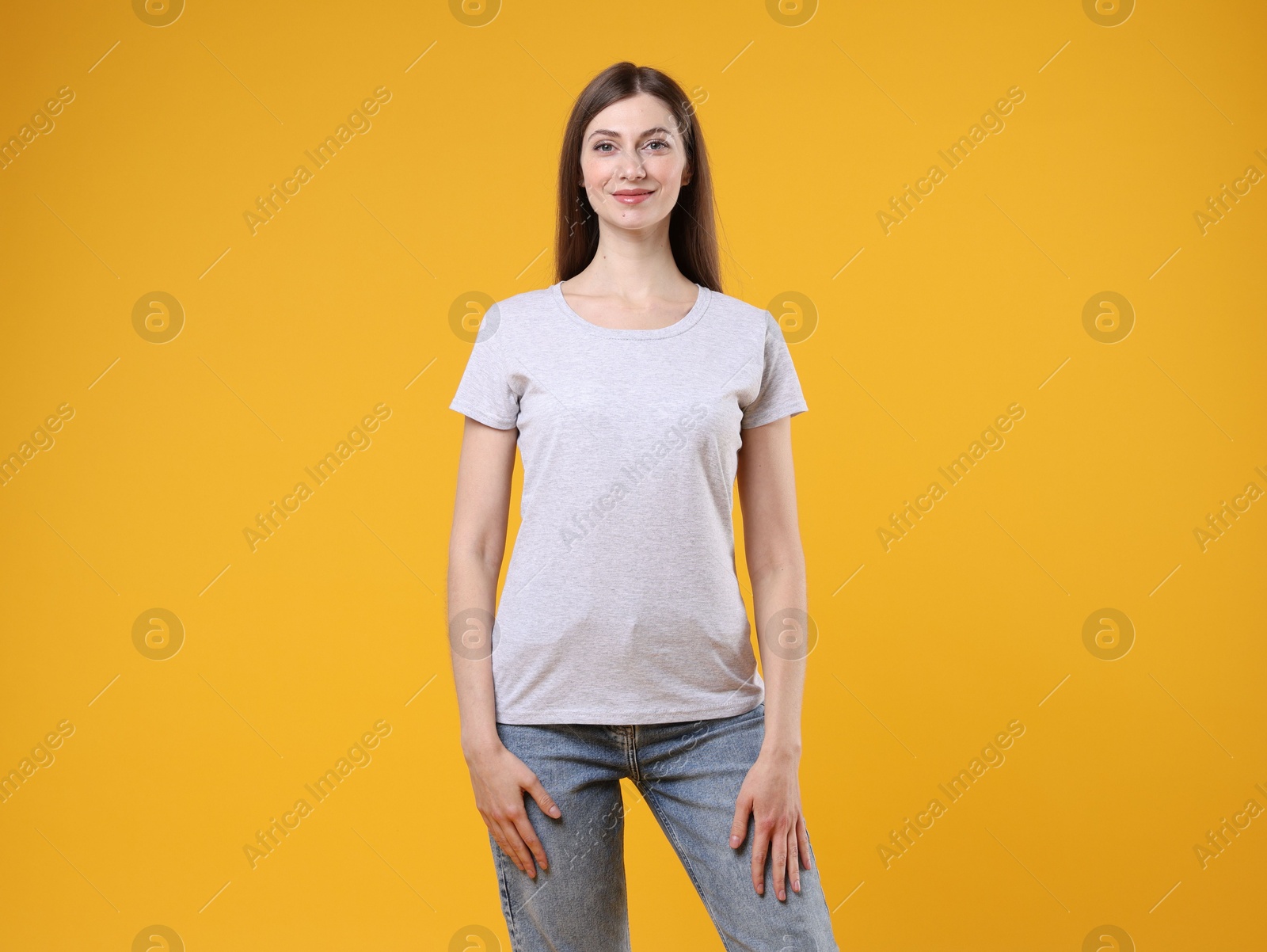 Photo of Woman wearing blank white t-shirt on orange background. Mockup for design