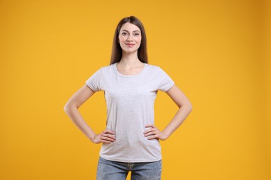 Photo of Woman wearing blank white t-shirt on orange background. Mockup for design