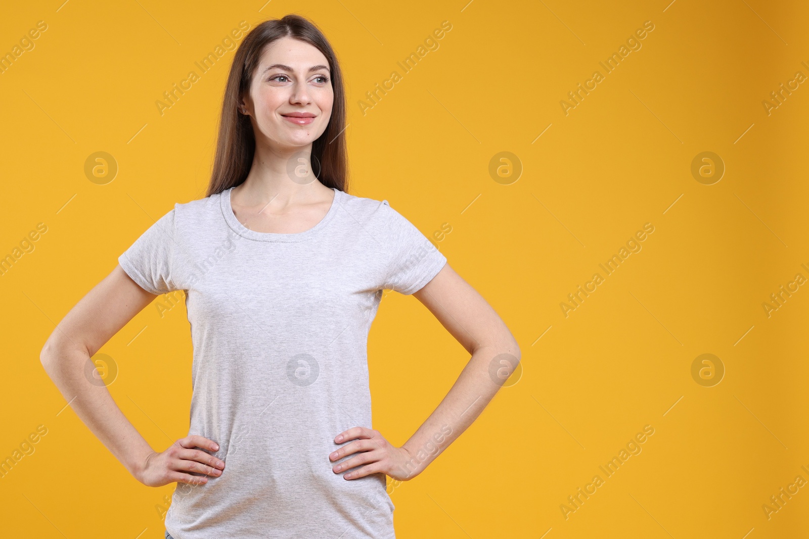 Photo of Woman wearing blank white t-shirt on orange background. Mockup for design