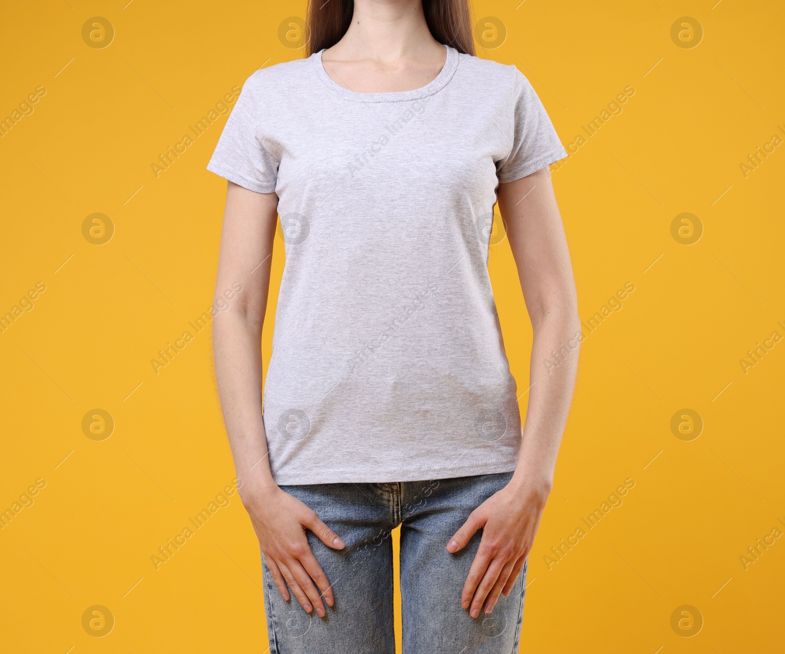 Photo of Woman wearing blank white t-shirt on orange background, closeup. Mockup for design